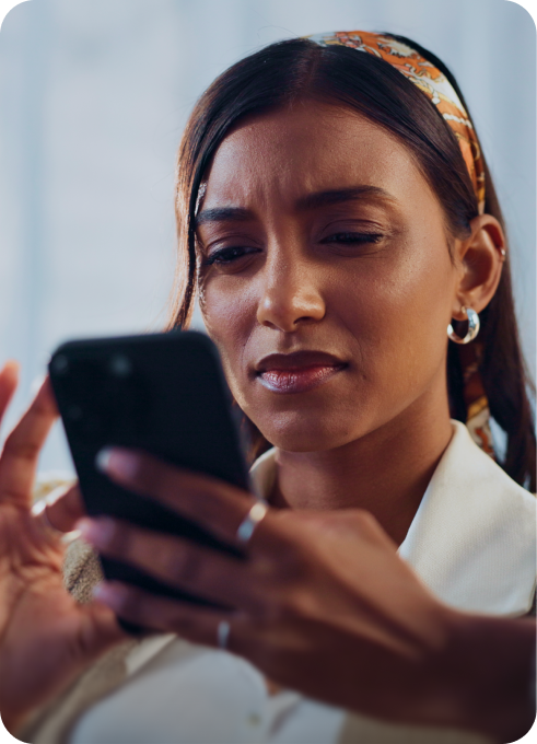 A woman looks at her phone with a skeptical expression, checking a suspicious message